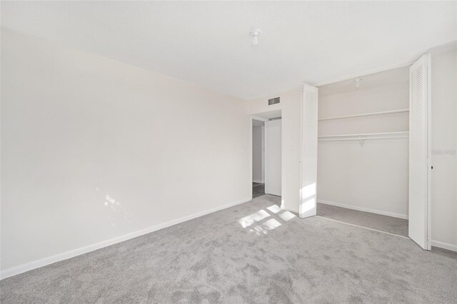 unfurnished bedroom featuring light carpet and a closet