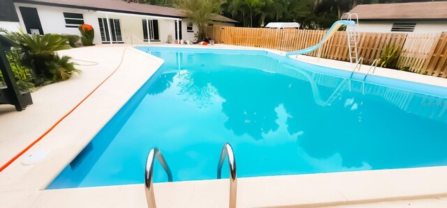 view of swimming pool featuring a water slide and a patio area