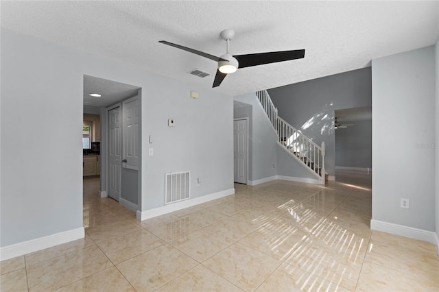 spare room with a textured ceiling, light tile patterned floors, and ceiling fan