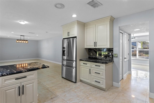 kitchen with tasteful backsplash, a textured ceiling, light tile patterned flooring, and stainless steel fridge