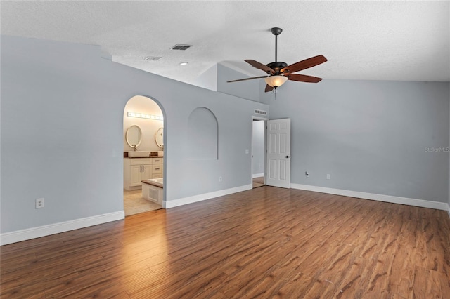 empty room featuring vaulted ceiling, a textured ceiling, light hardwood / wood-style floors, and ceiling fan