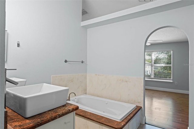 bathroom with a textured ceiling, hardwood / wood-style flooring, sink, and a tub