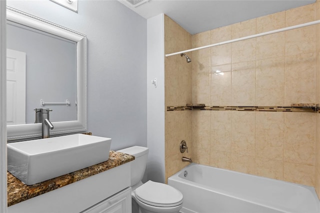 full bathroom featuring vanity, tiled shower / bath, and toilet