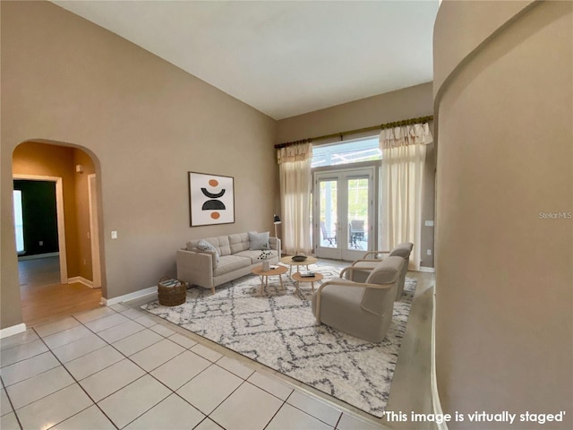 tiled living room featuring lofted ceiling and french doors