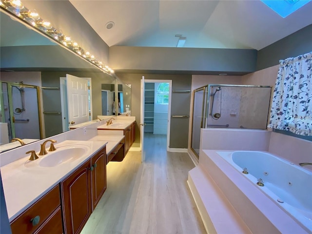 bathroom with independent shower and bath, lofted ceiling with skylight, vanity, and wood-type flooring