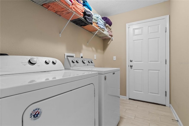 clothes washing area with independent washer and dryer, a textured ceiling, and light hardwood / wood-style floors