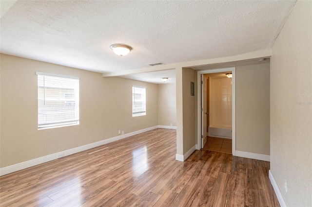 unfurnished room with a textured ceiling and hardwood / wood-style floors