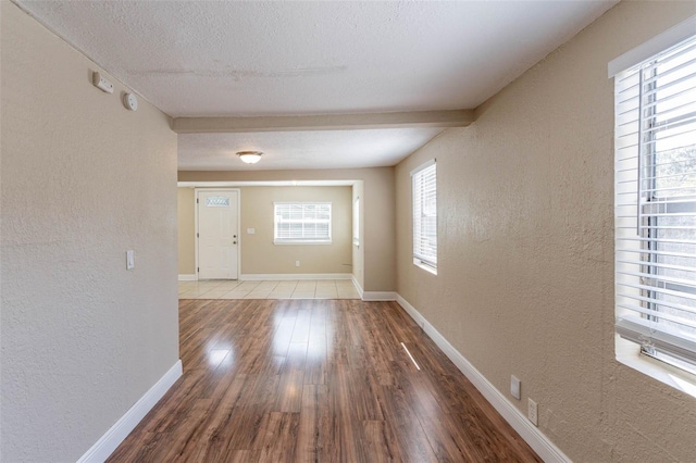 interior space with hardwood / wood-style floors, beam ceiling, and a textured ceiling