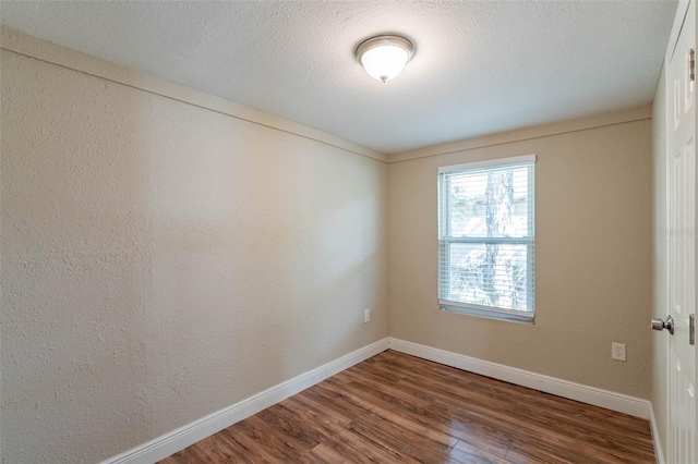 spare room with dark wood-type flooring and a textured ceiling