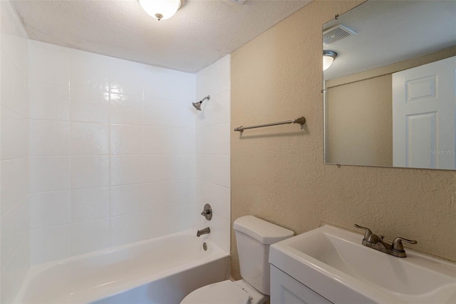 full bathroom featuring toilet, tiled shower / bath, a textured ceiling, and vanity