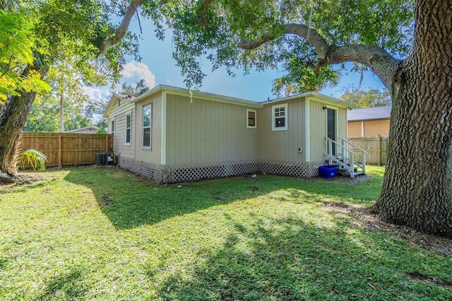 back of house featuring a yard and central AC