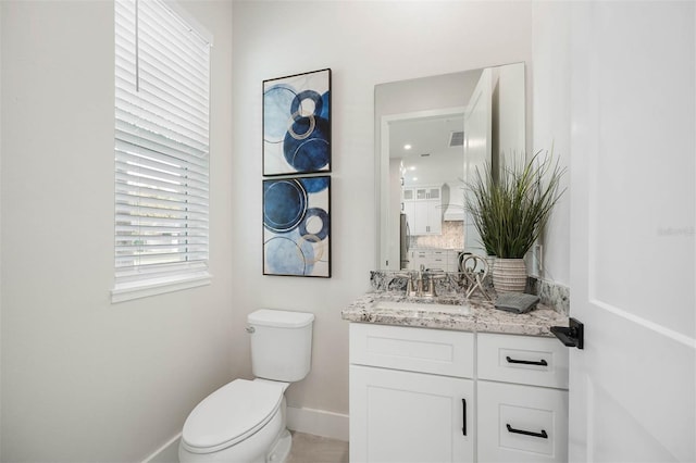 bathroom featuring vanity, toilet, and backsplash