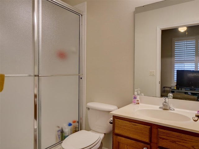 bathroom with a shower with door, vanity, and toilet