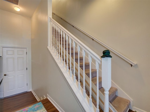 staircase featuring wood finished floors, visible vents, and baseboards