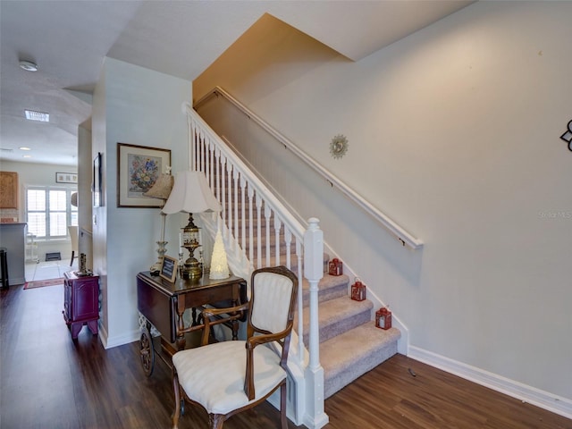 stairway featuring visible vents, baseboards, and wood finished floors