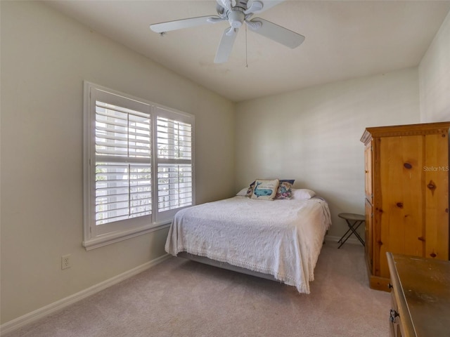 bedroom with a ceiling fan, light colored carpet, and baseboards