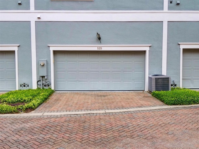 garage featuring decorative driveway and cooling unit