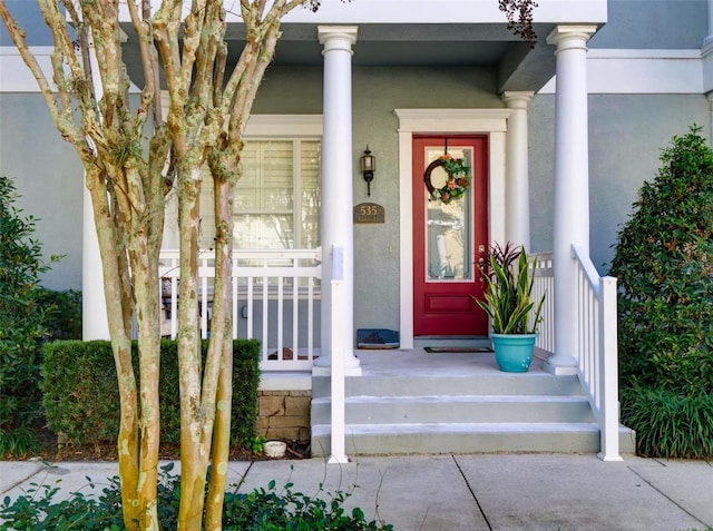 entrance to property featuring covered porch and stucco siding