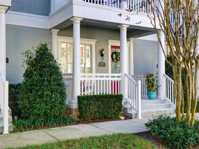 view of exterior entry with covered porch and stucco siding