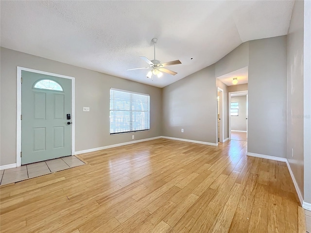 foyer entrance with lofted ceiling, a textured ceiling, light wood-type flooring, and ceiling fan