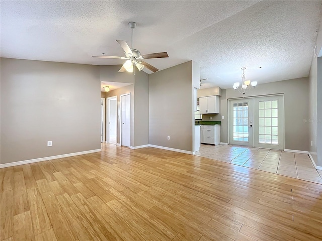 unfurnished living room with french doors, light hardwood / wood-style floors, a textured ceiling, and ceiling fan with notable chandelier