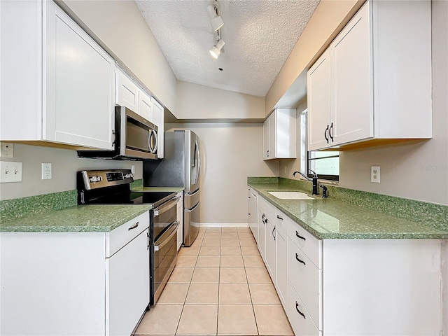 kitchen with lofted ceiling, sink, white cabinets, appliances with stainless steel finishes, and a textured ceiling