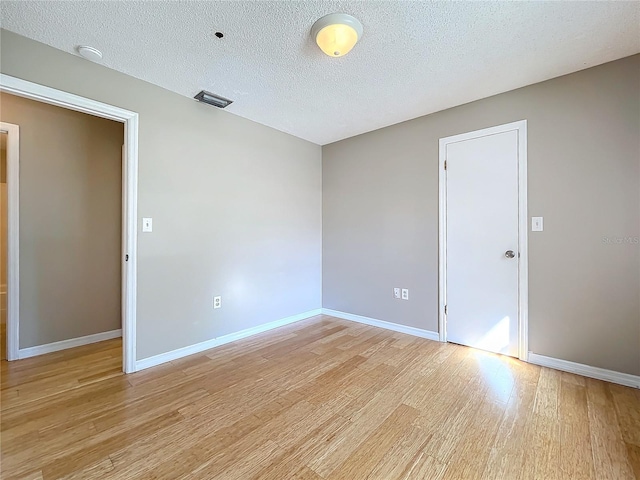 empty room with a textured ceiling and light wood-type flooring