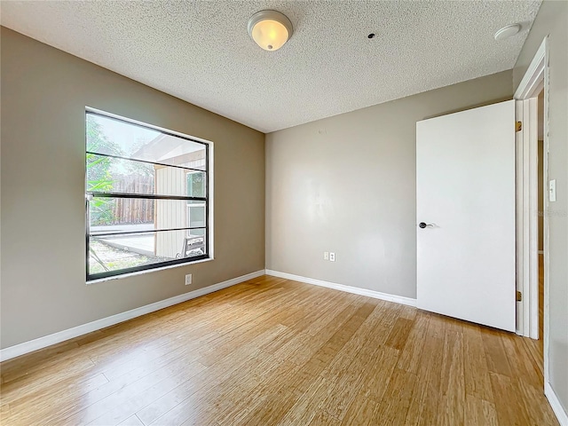 spare room with a textured ceiling and light wood-type flooring