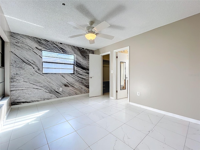 spare room featuring ceiling fan, a textured ceiling, and tile walls