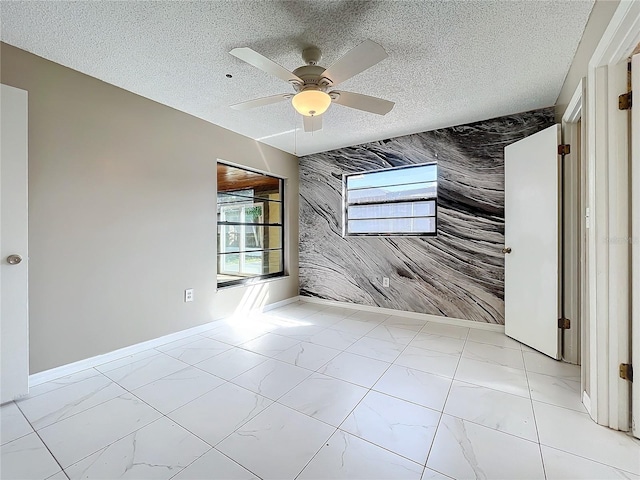 spare room featuring ceiling fan, a textured ceiling, and tile walls