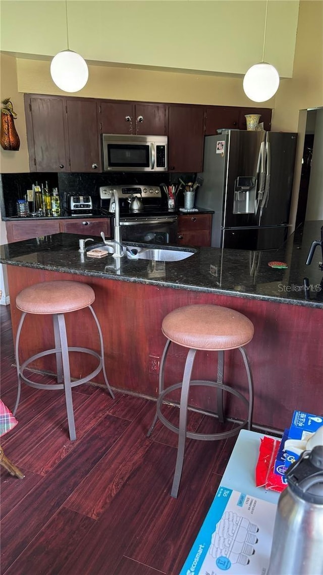 kitchen with stainless steel appliances, decorative light fixtures, and a breakfast bar area