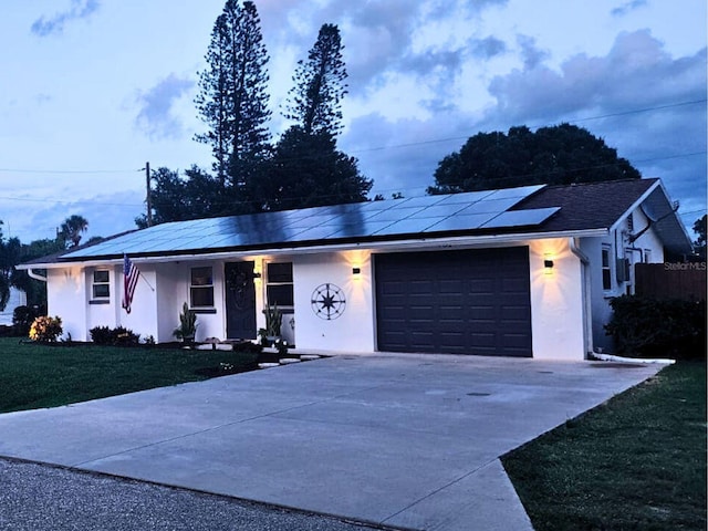 ranch-style house with solar panels, a garage, and a front lawn