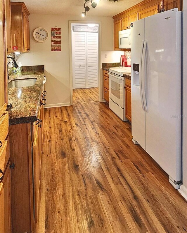 kitchen featuring a textured ceiling, sink, white appliances, and light wood-type flooring