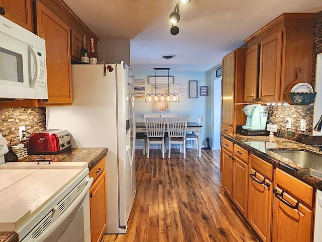 kitchen with sink, dark hardwood / wood-style floors, backsplash, a textured ceiling, and white appliances