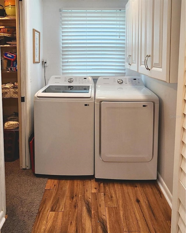 laundry area featuring cabinets, hardwood / wood-style flooring, and washer and dryer