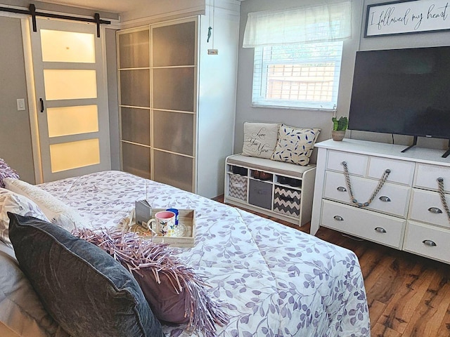 bedroom featuring a barn door and dark hardwood / wood-style flooring