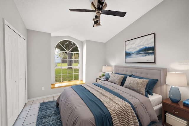 bedroom featuring tile patterned flooring, baseboards, ceiling fan, lofted ceiling, and a closet