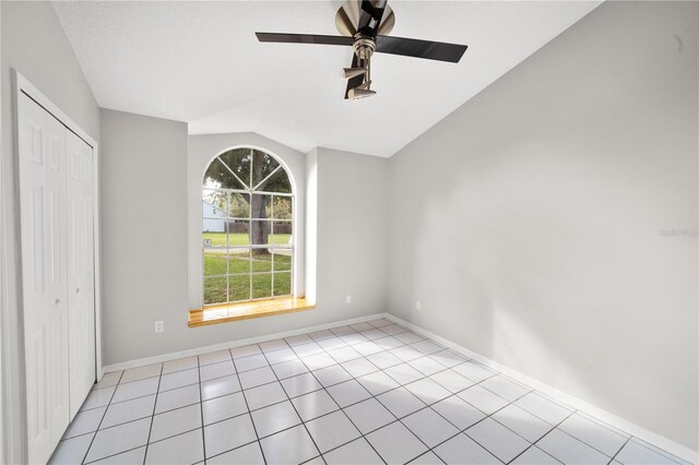 unfurnished dining area with lofted ceiling, light tile patterned flooring, a ceiling fan, and baseboards