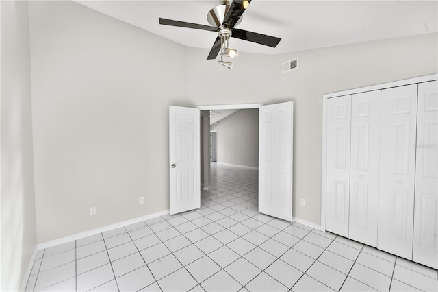 unfurnished bedroom with visible vents, vaulted ceiling, light tile patterned floors, a closet, and a ceiling fan