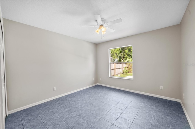 tiled spare room with baseboards and ceiling fan
