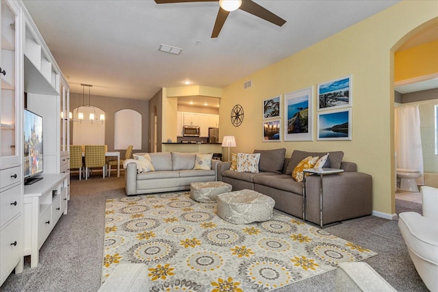 living room with carpet and ceiling fan with notable chandelier