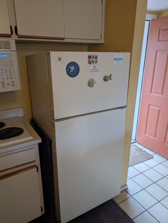 kitchen with white cabinets, white fridge, and light tile patterned flooring