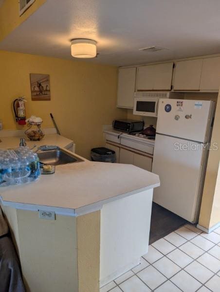 kitchen featuring white cabinets, kitchen peninsula, white appliances, and light tile patterned floors