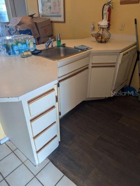 kitchen with white cabinetry, kitchen peninsula, hardwood / wood-style floors, and sink