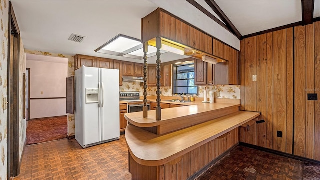 kitchen featuring kitchen peninsula, stainless steel electric stove, white fridge with ice dispenser, wooden walls, and sink