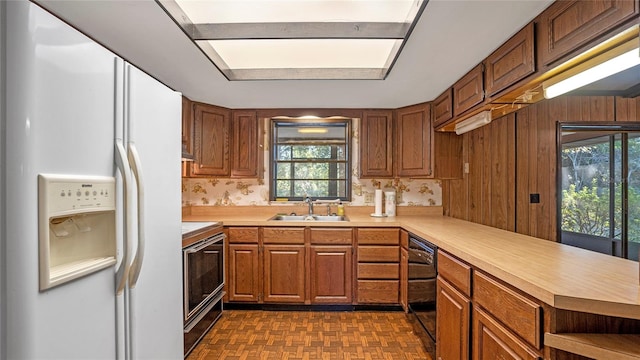 kitchen featuring a wealth of natural light, sink, stainless steel range, and white refrigerator with ice dispenser