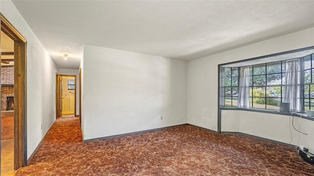 empty room featuring carpet flooring and a brick fireplace