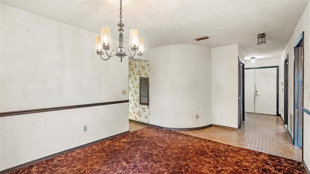 carpeted empty room featuring a notable chandelier