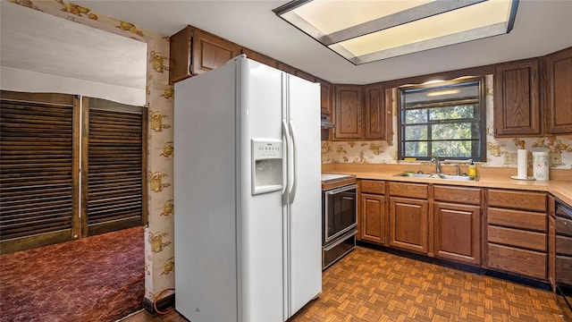 kitchen featuring sink, stainless steel range oven, dark parquet flooring, and white fridge with ice dispenser