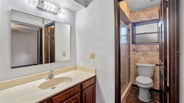 bathroom with toilet, a shower with shower door, vanity, and tile patterned flooring